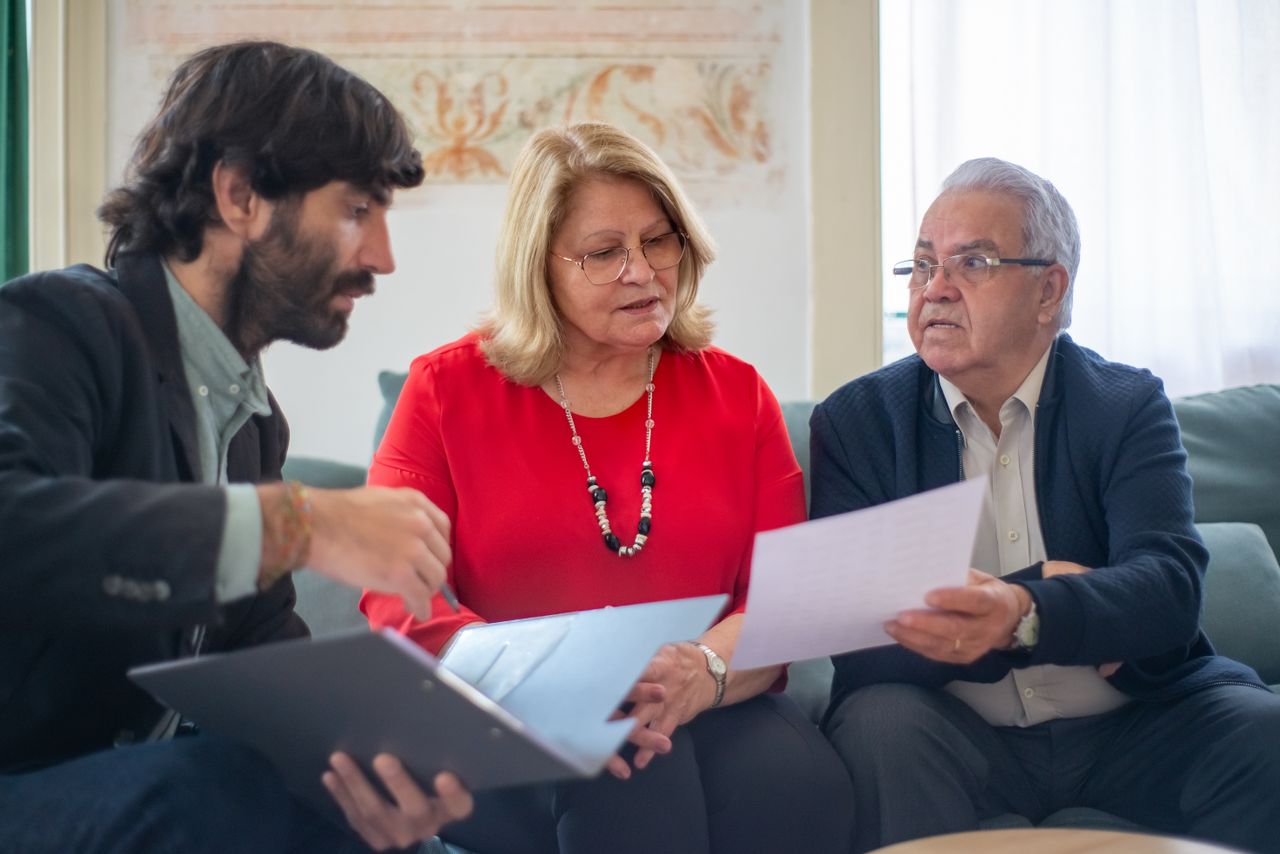 Senior couple consulting with a professional advisor, discussing documents indoors.