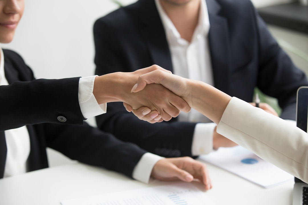 two-people-shaking-hands-in-front-of-a-laptop-xeq8xewb4q